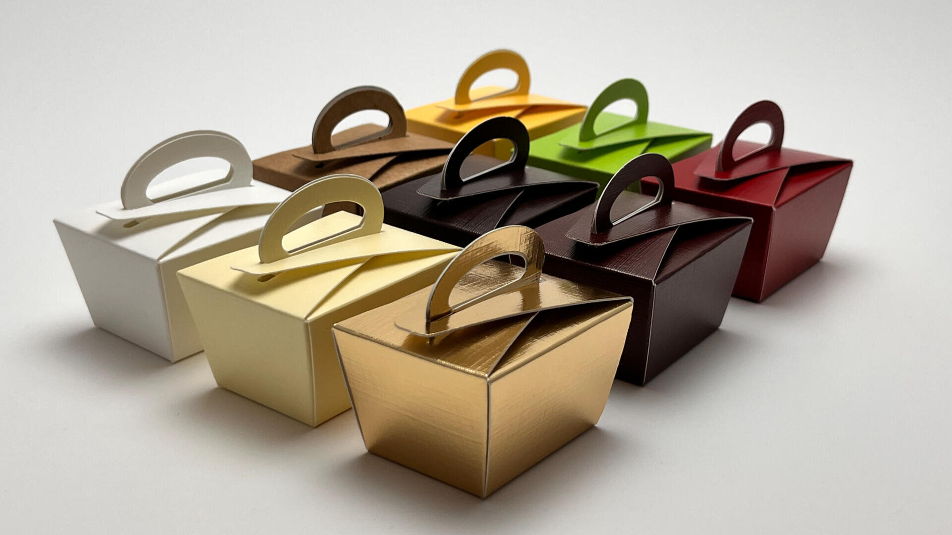 Acht kleine Geschenkboxen in verschiedenen Farben – darunter Weiß, Elfenbein, Gold, Braun, Gelb, Grün, Burgunderrot und Rot – sind in zwei Reihen auf weißem Grund angeordnet. Jede Box hat oben einen passenden Griff.