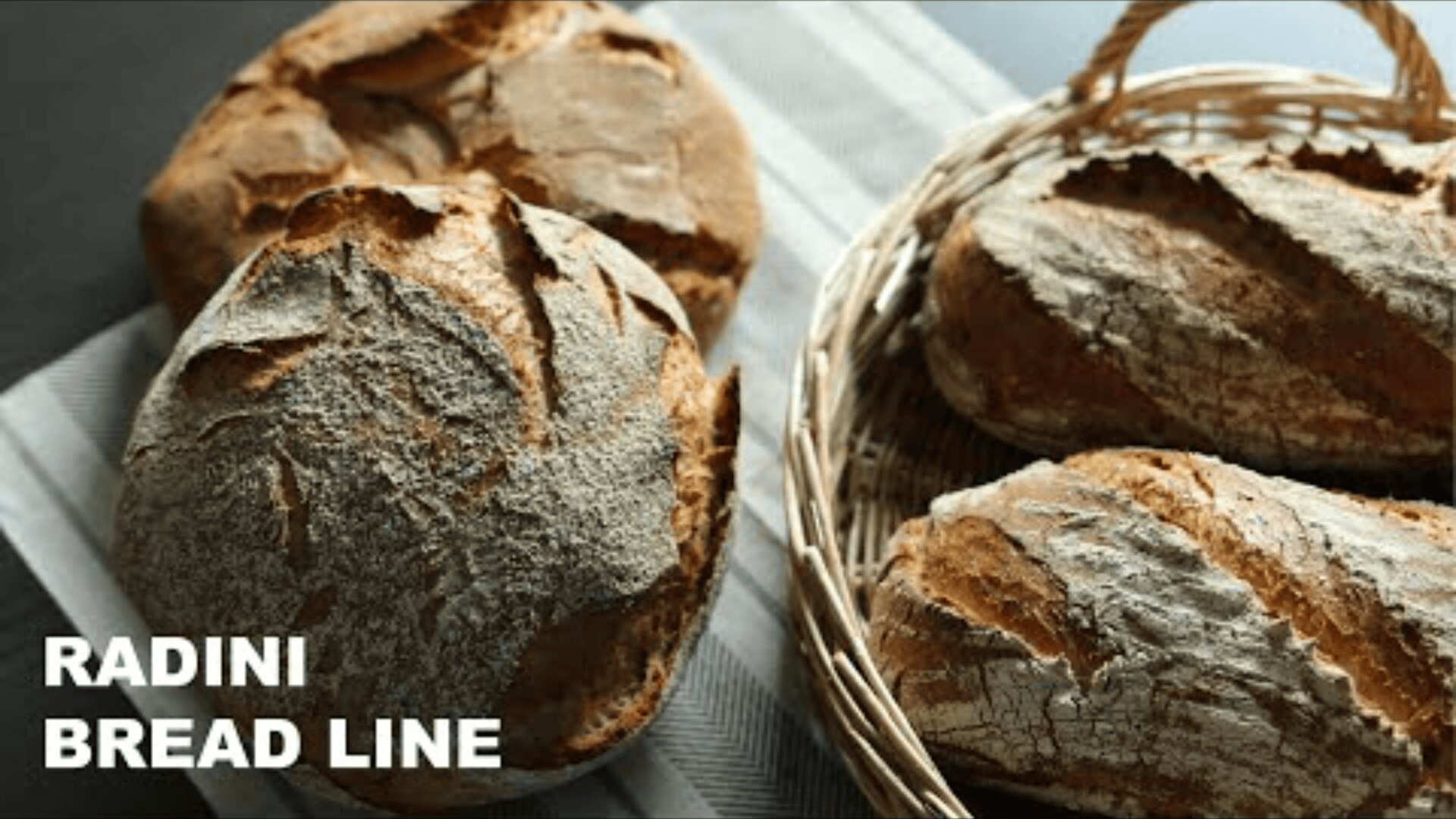 On a striped cloth and in a woven basket lie round and oblong, artisan-baked loaves. The bread has a crispy, flour-dusted surface. The text RADINI BREAD LINE is written in the bottom left-hand corner.