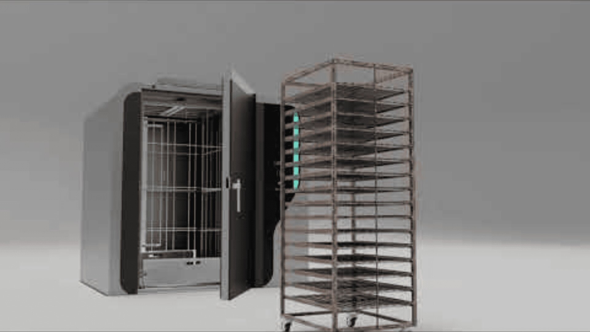 A large industrial oven with its door open is positioned next to a metal rack filled with trays, standing on a light-colored floor against a plain gray background.