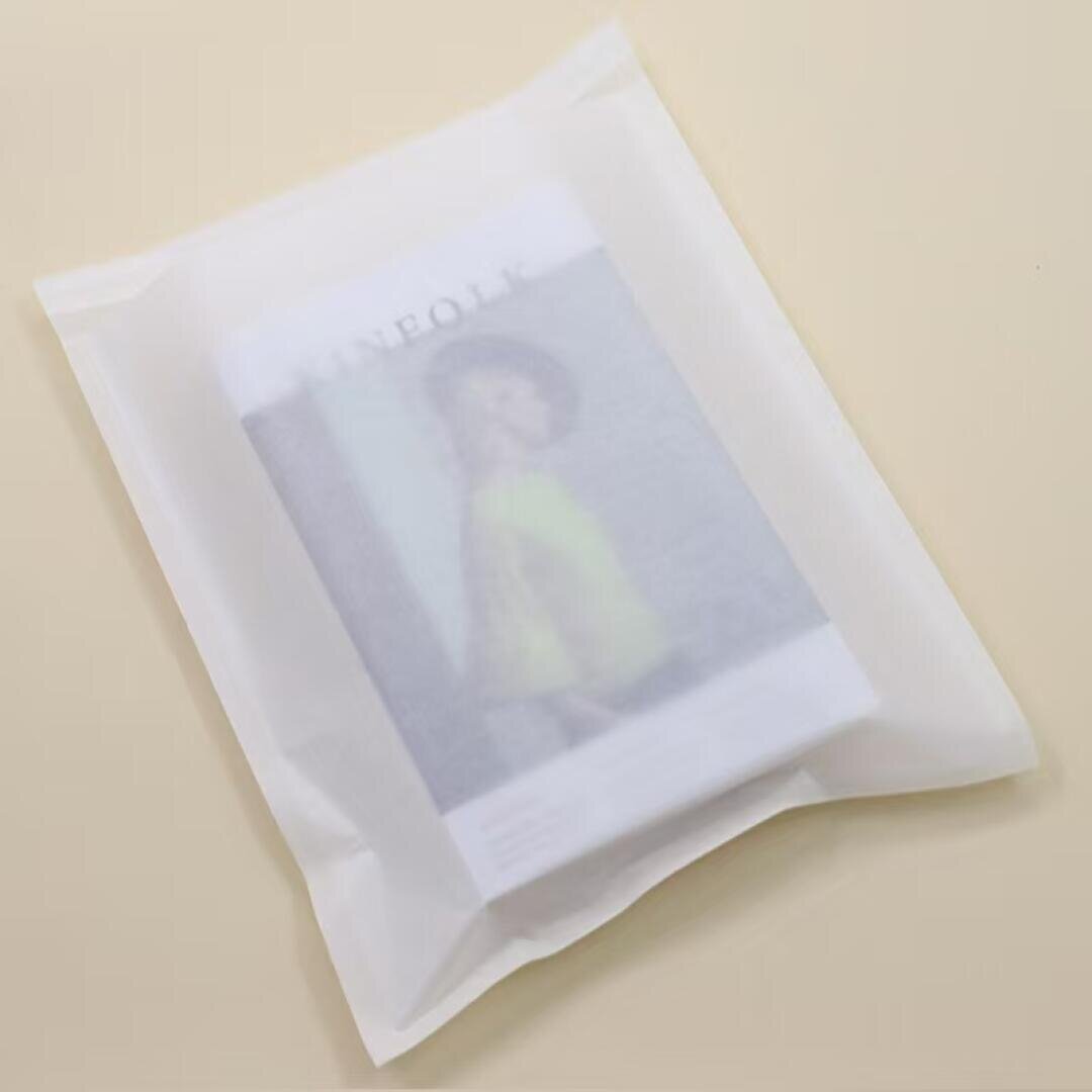 A white translucent plastic pouch containing a magazine or brochure with a blurred image of a person on the cover, placed on a light beige surface.