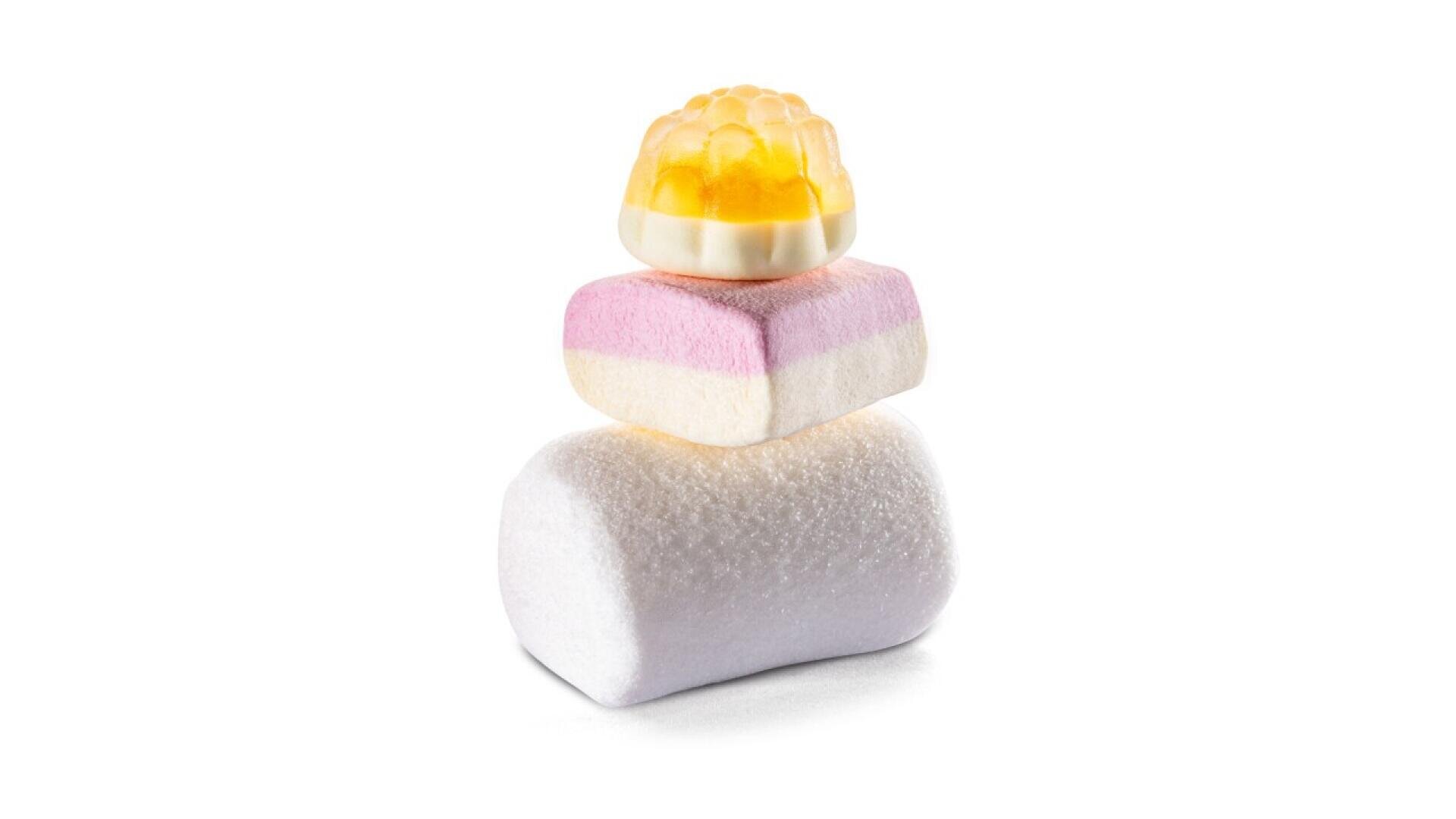 A stack of three candies: a white marshmallow at the bottom, a rectangular pink-and-white marshmallow in the middle, and a yellow gummy candy shaped like a flower on top, all on a white background.