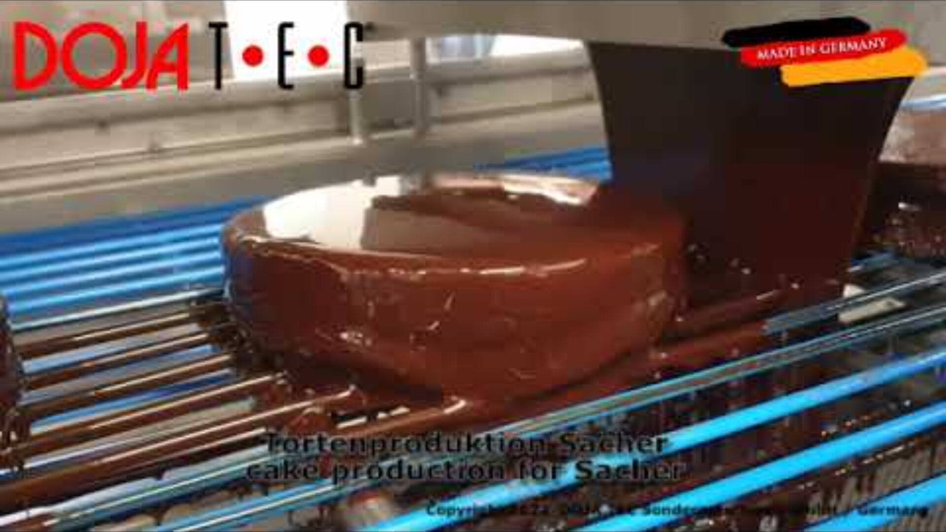 A Sacher cake moves along a conveyor belt while being coated with liquid chocolate. The words DOJA TEC and Made in Germany appear at the top, with text about Sacher cake production at the bottom.
