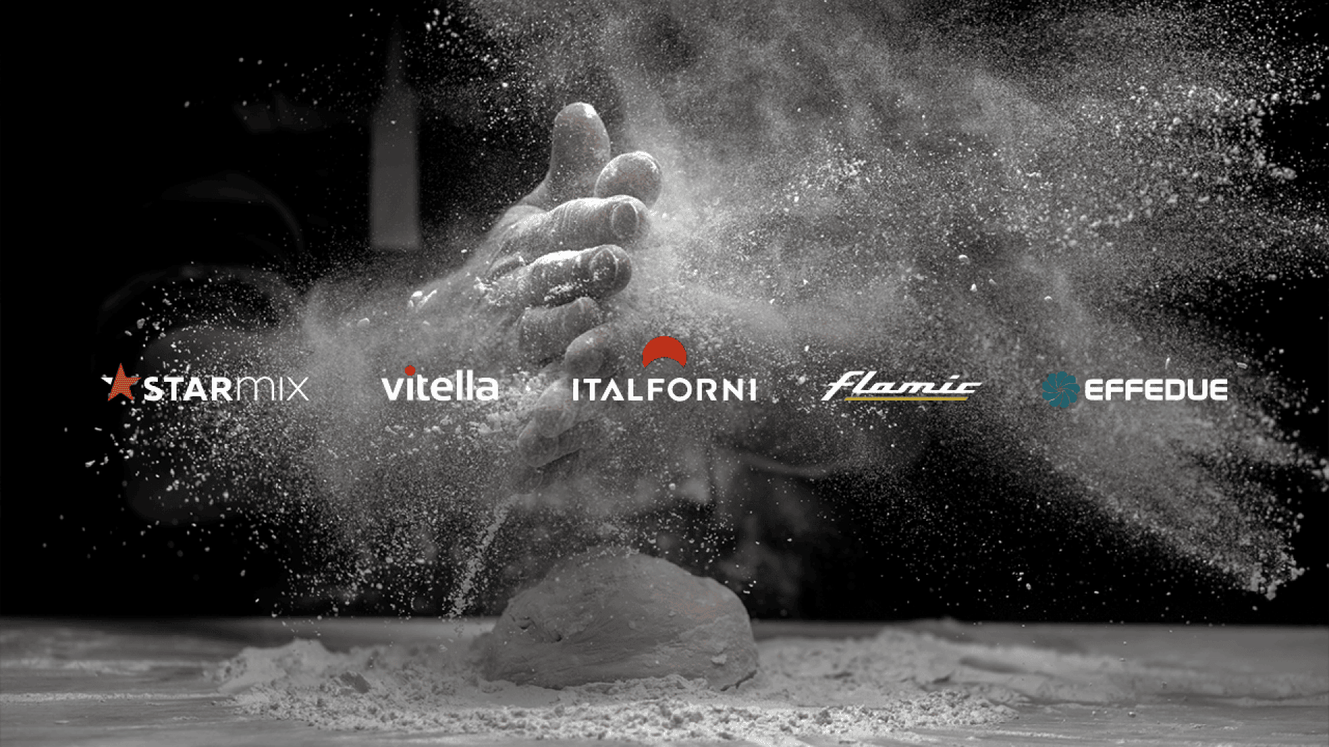 Mit Mehl bedeckte Hände klatschen über den Teig auf einer bemehlten Fläche, wodurch eine Mehlwolke entsteht. Fünf Logos - Starmix, Vitella, Italforni, Flamic und Effedue - sind auf dem Bild zu sehen.
