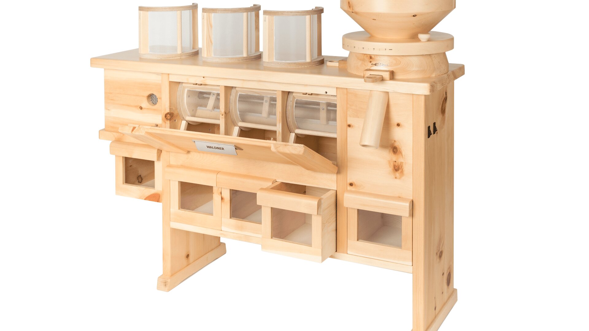 Eine hölzerne Getreidemühle mit drei durchsichtigen Vorratsbehältern auf der Oberseite, einem großen Trichter auf der rechten Seite und mehreren Fächern und Schubladen zum Auffangen des gemahlenen Mehls darunter.