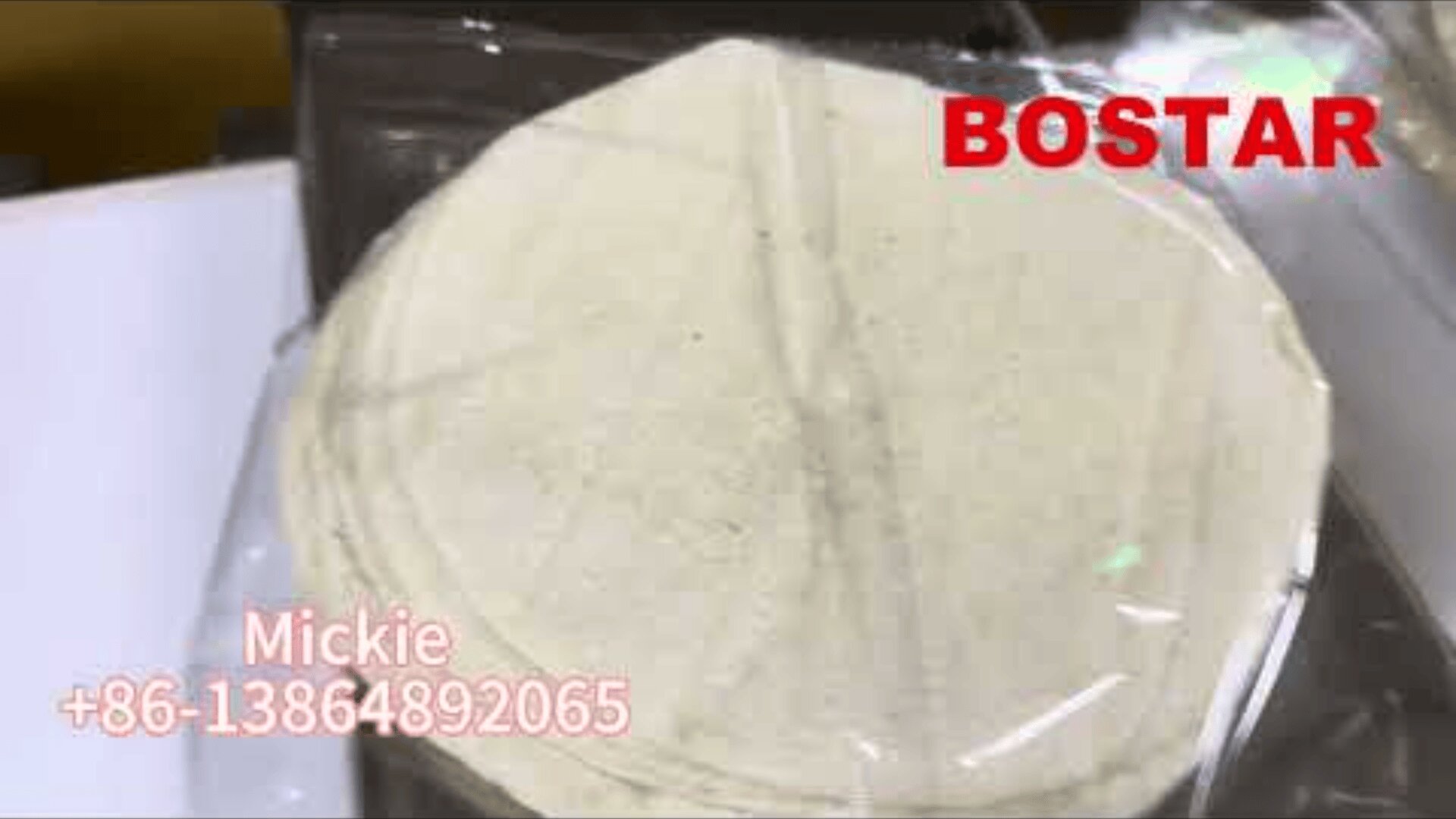 A stack of round, white tortillas wrapped in clear plastic, with the word BOSTAR in red at the top right and contact information for Mickie with a phone number in pink text at the bottom left.