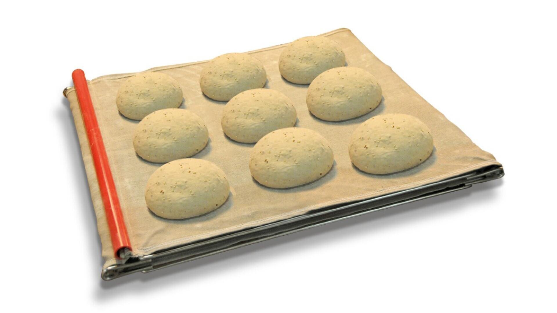 Ten round dough balls rest on a floured cloth couche with metal supports and a red rolling pin along one side, set against a white background.
