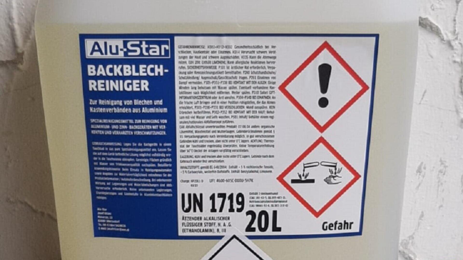 A large container of Alu-Star Backblech-Reiniger cleaning solution with German text, hazard symbols for corrosive material and warning, and a label indicating 20 liters and UN 1719.