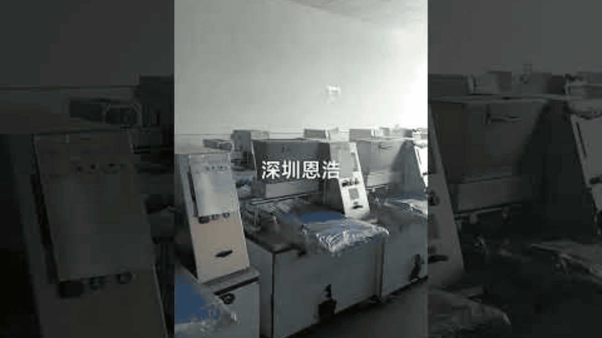 Several industrial machines are lined up in a dimly lit room. Chinese characters are displayed in the center of the image. The machines appear to be unused or in storage.