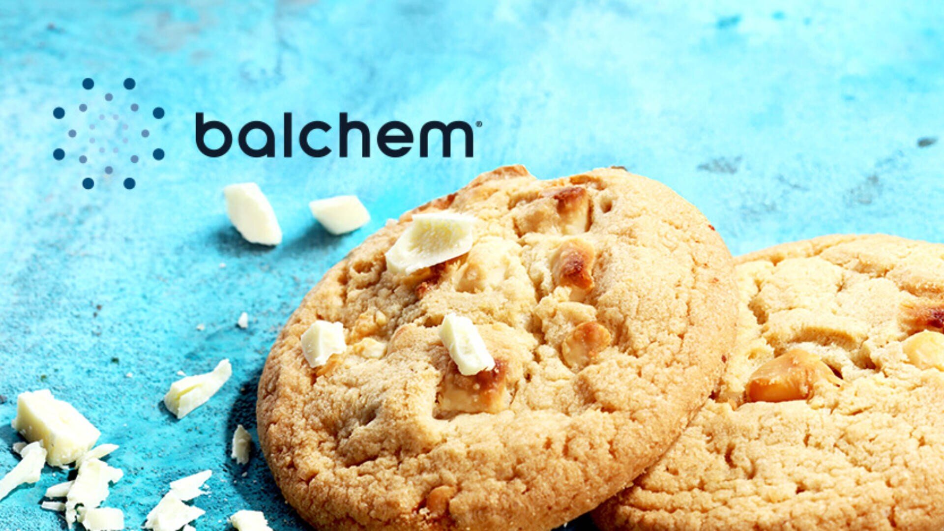 Two white chocolate chip cookies and chocolate chunks on a bright blue textured surface, with the Balchem logo in the upper left corner.