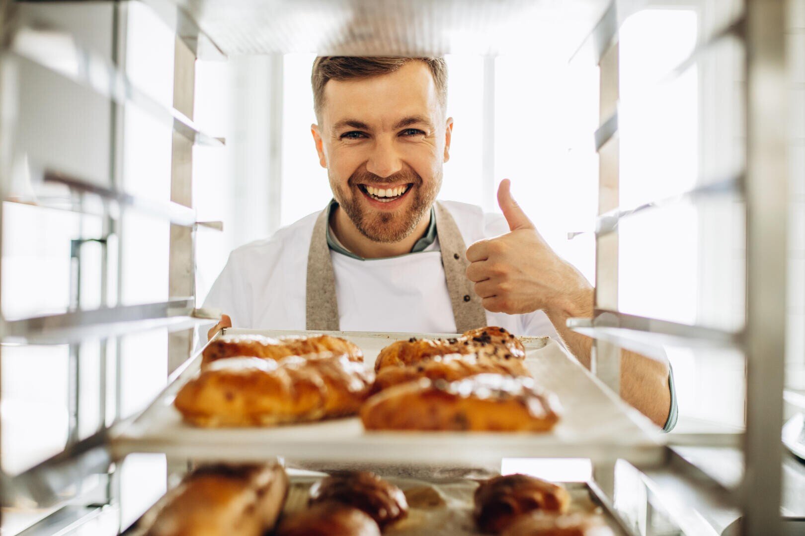 Man baker at the kitchen by the pastry cart