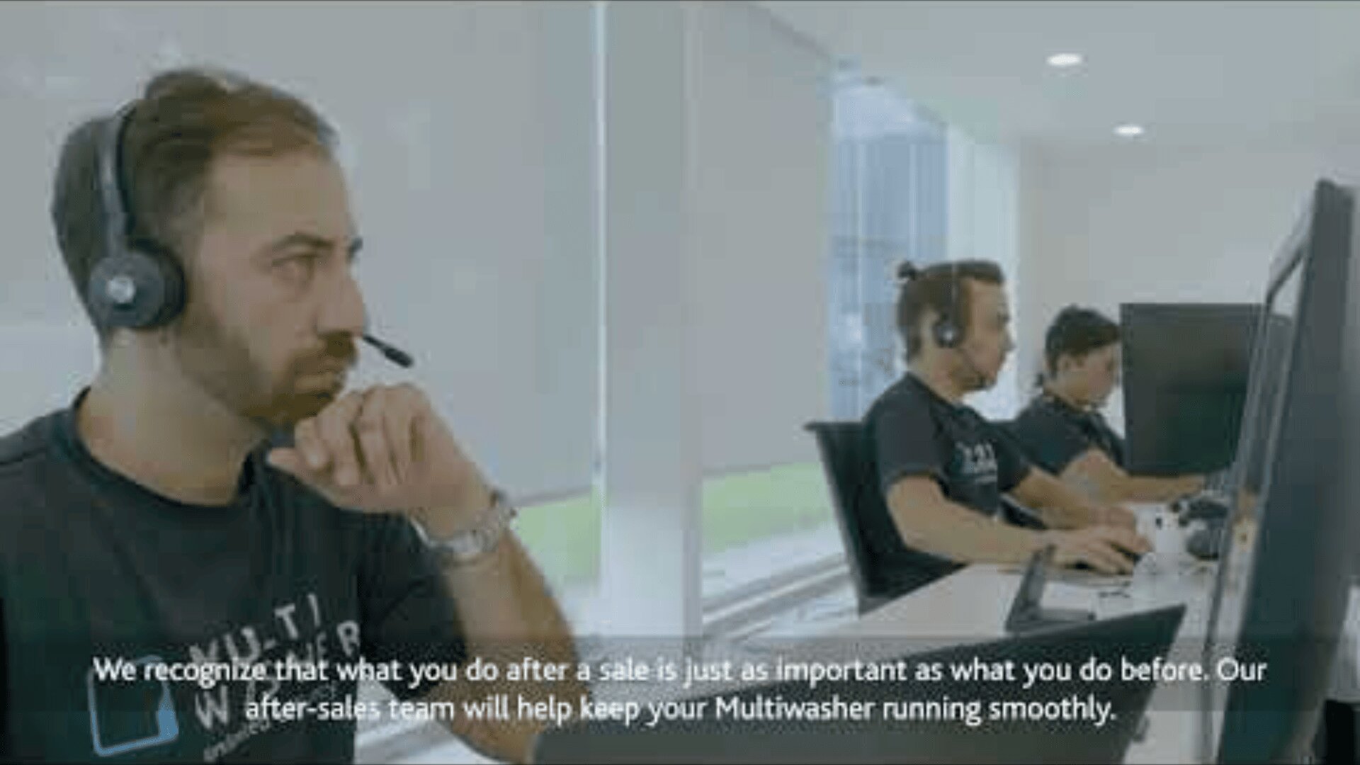 Three men wearing headsets sit at desks working on computers in a bright, modern office. Text at the bottom mentions the importance of after-sales support for Multiwasher products.