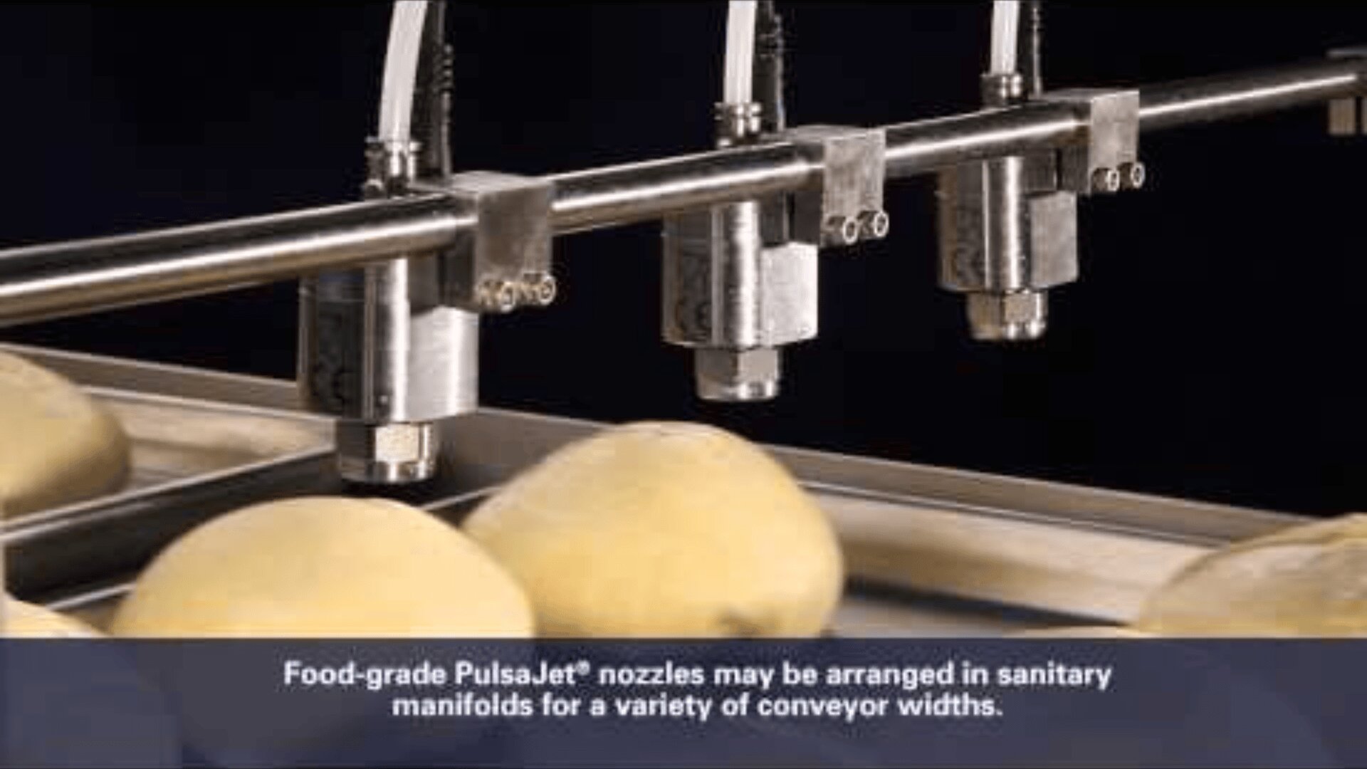 Close-up of food-grade PulsaJet nozzles spraying over potatoes on a conveyor belt, with a caption describing the nozzles arrangement for different conveyor widths.