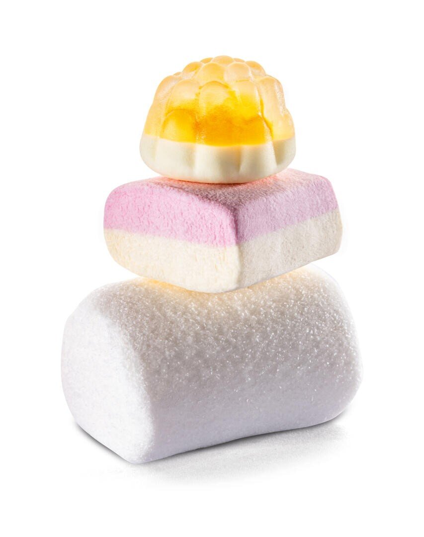 Three colorful candies stacked: a yellow and white gummy on top, a pink and white layered marshmallow in the middle, and a plain white cylindrical marshmallow on the bottom, all on a white background.