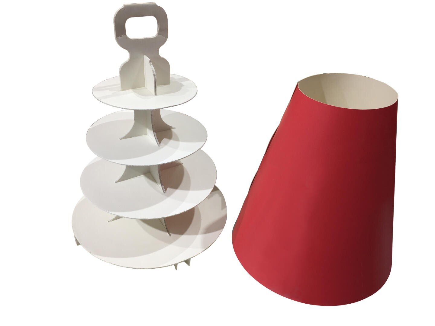 A white, four-tiered cardboard cupcake stand with a handle on top stands next to a red, cone-shaped paper cover or wrapper. Both objects are positioned on a white background.