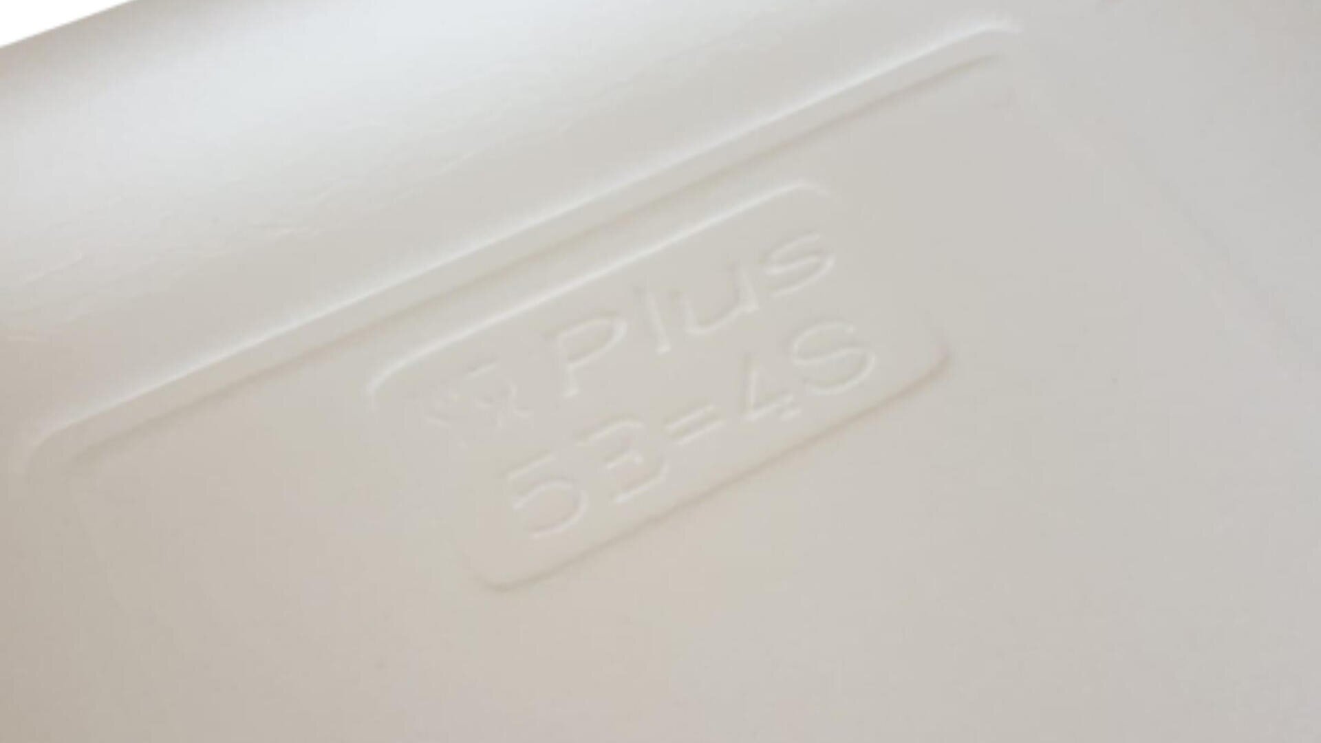 Close-up of a white surface with the embossed text PLUS 53=4S clearly visible in the center.