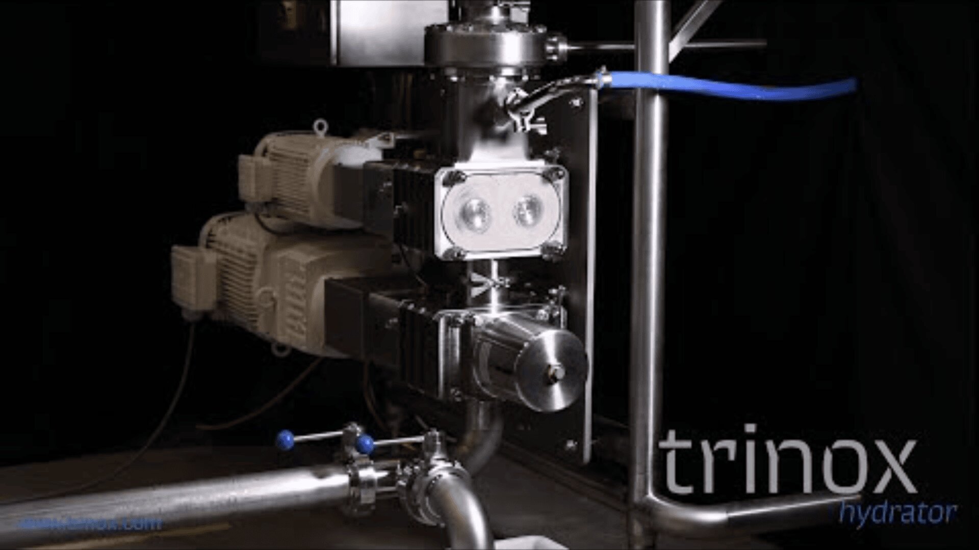 A close-up view of industrial stainless steel machinery with pipes and valves, featuring the brand name “trinox hydrator” in the lower right corner, set against a dark background.