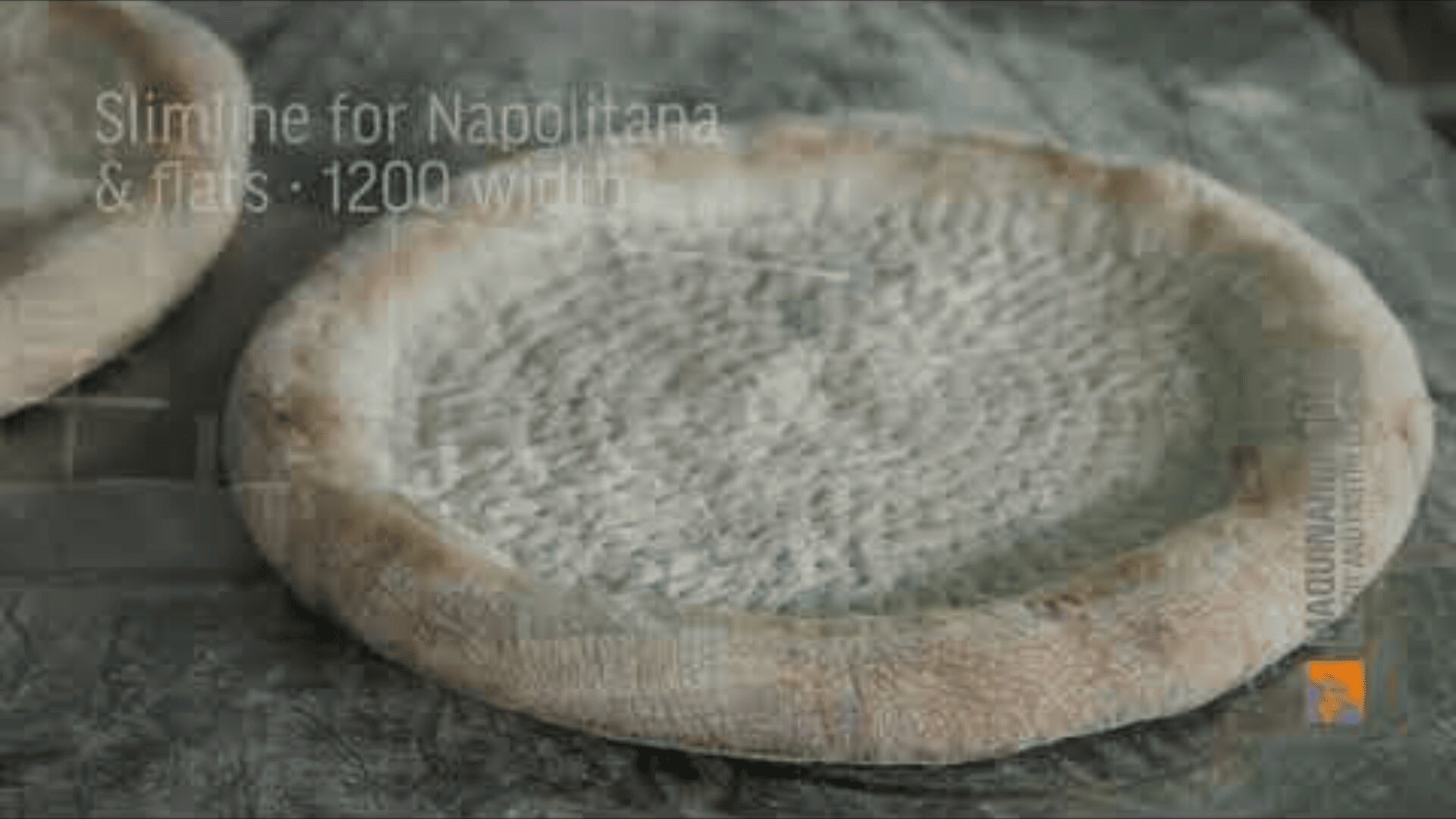 A raw, round pizza dough with a textured surface lies on a floured work surface, ready for the topping. A faint text appears above the image with the reference to Slimline for Napolitana & Flats: 1200 width.