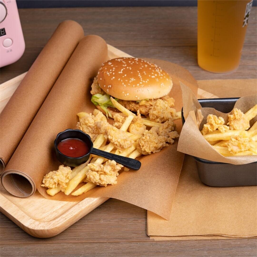 A meal with a sesame seed burger, crispy fried chicken pieces, French fries, a small container of ketchup, and a drink, all served on a wooden tray lined with brown paper.