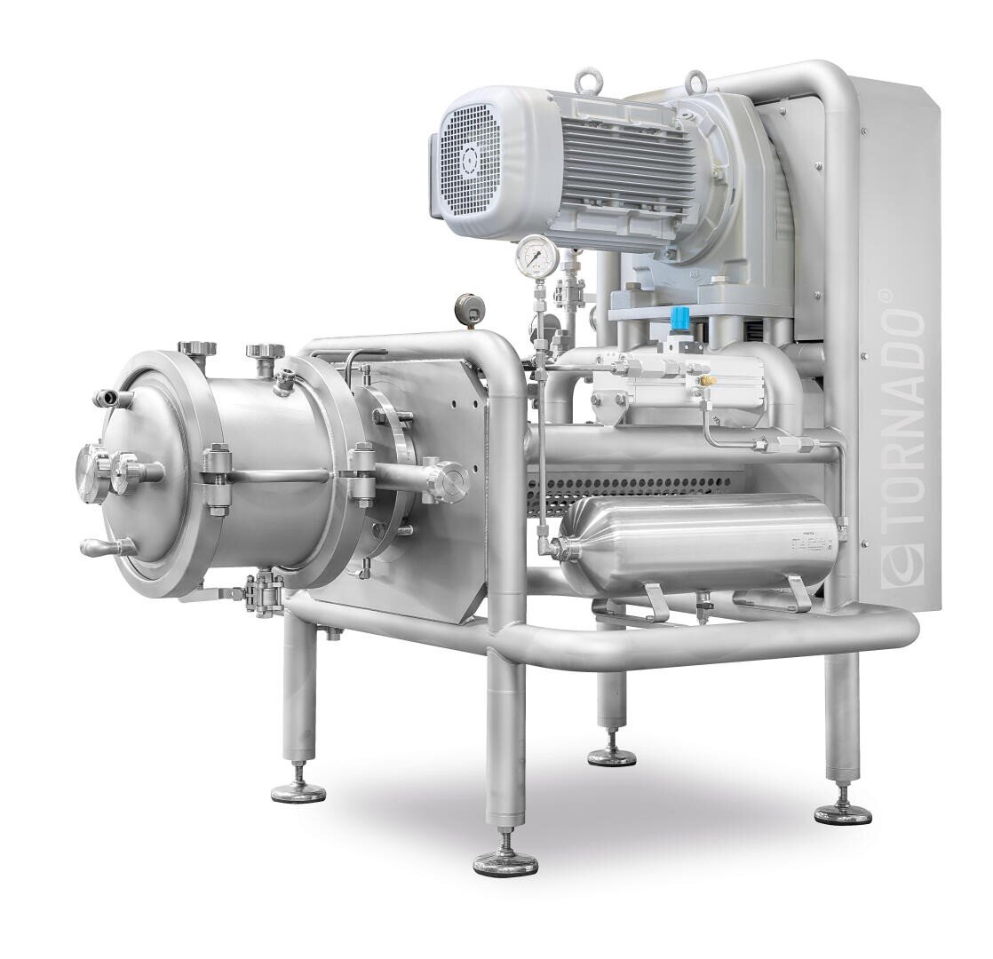 A large industrial stainless steel machine with pipes, gauges, and a motor, labeled TORNADO, stands on four sturdy legs, designed for processing or manufacturing applications.