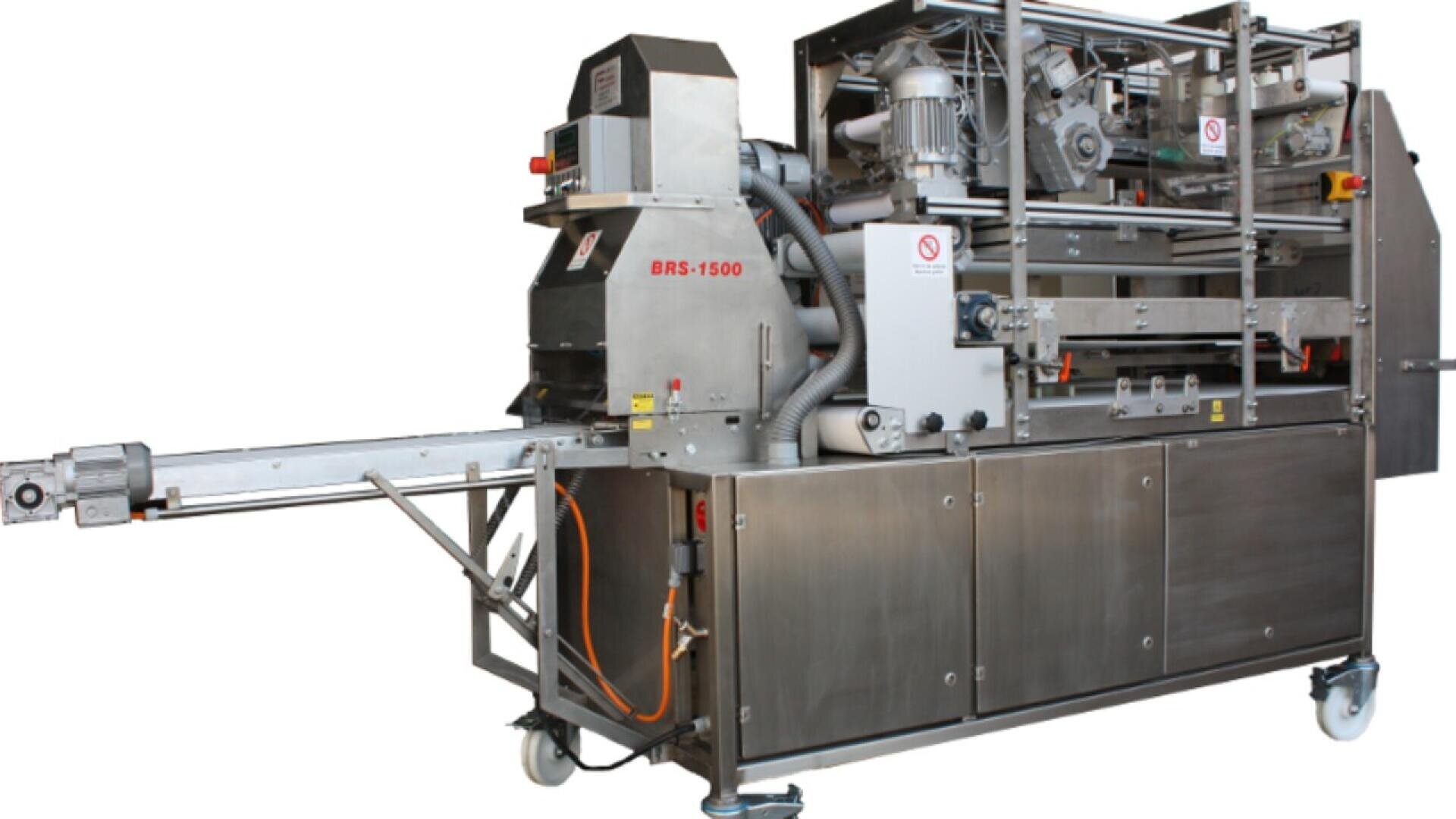 Large industrial stainless steel food processing machine with conveyors, motors, and control panel, labeled BRS-1500. The machine has various tubes, wires, and compartments, designed for automated production.