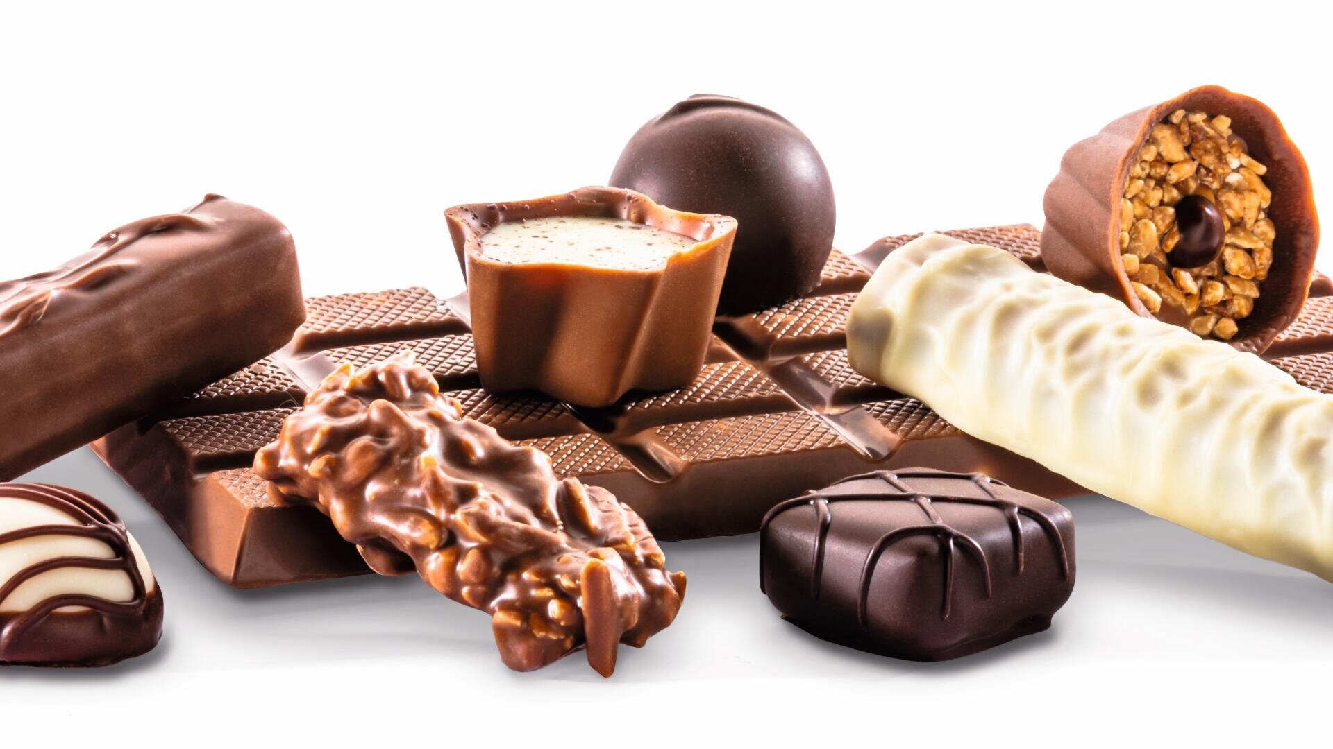 An assortment of chocolates and chocolate bars, including milk, dark, and white chocolate pieces with various shapes and textures, arranged on a white background.