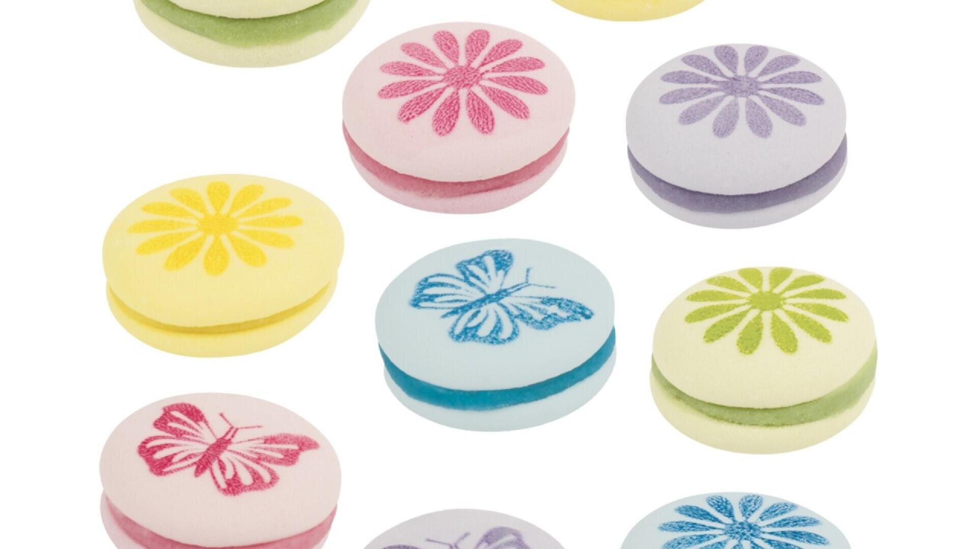 Assorted pastel-colored sandwich cookies decorated with printed flowers and butterflies on top, arranged on a white background.