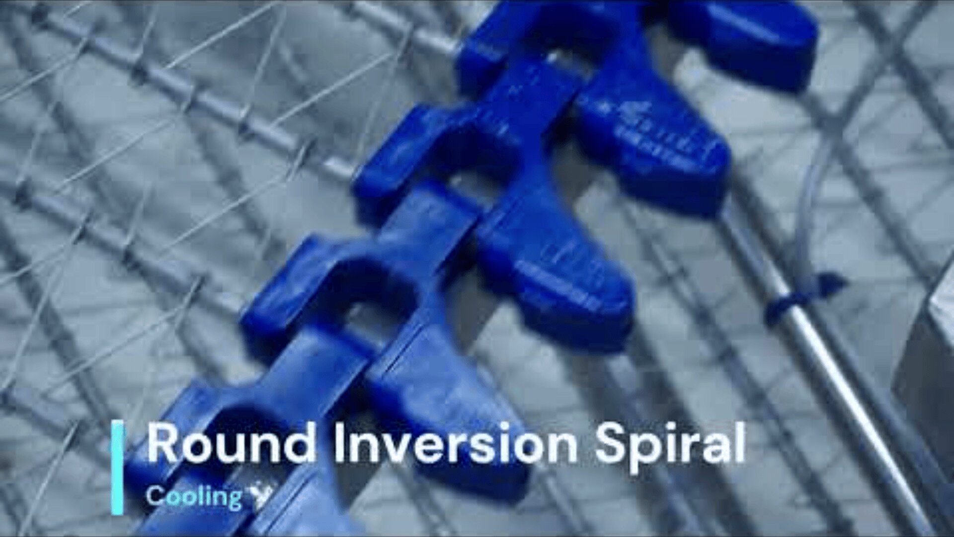 Close-up of blue plastic links on an industrial conveyor system with metal wires and rods, labeled “Round Inversion Spiral” and “Cooling” in the corner.