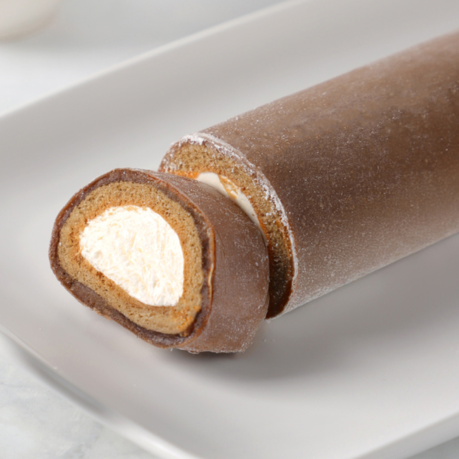 Auf einem weißen Teller liegt eine Schokoladen-Biskuitrolle mit cremeweißer Füllung, wobei ein Stück angeschnitten ist, um die Wirbelschichten aus Kuchen und Füllung zu zeigen.